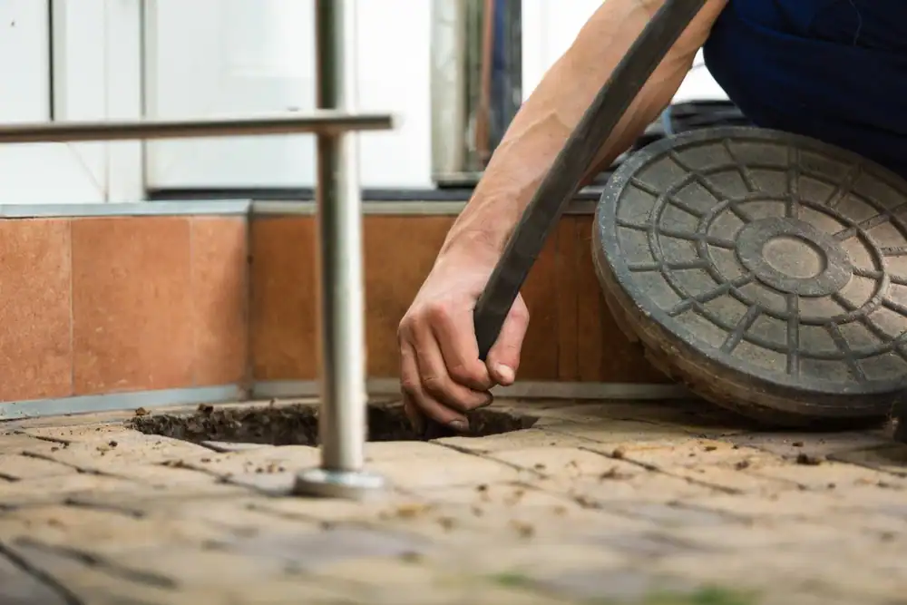 FloTek Plumbing technicians performing professional drain cleaning and pipe repair in residential and commercial properties. The image shows a plumber using a plumbing snake and other specialized tools to clear a clogged drain, while another technician inspects pipes for damage. The setting includes modern bathrooms and kitchens with exposed plumbing fixtures, emphasizing expert service and efficient maintenance.